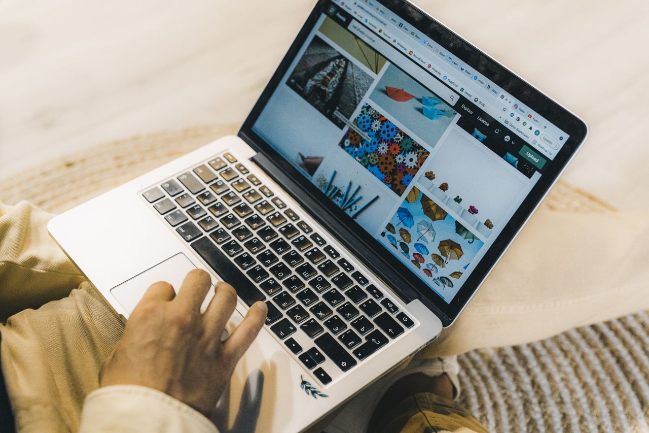 Une personne utilisant un ordinateur portable pour parcourir des sites de photos libres de droits. Travail en freelance dans un cadre chaleureux.